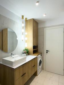 a bathroom with a sink and a washing machine at The Calaya - Aparthotel Saranda in Sarandë
