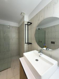 a white bathroom with a sink and a mirror at The Calaya - Aparthotel Saranda in Sarandë