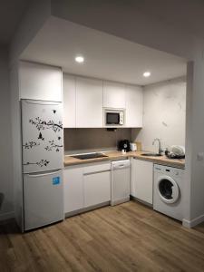 a kitchen with white cabinets and a washer and dryer at Apartamento La Mandrágora in Arenas de Cabrales