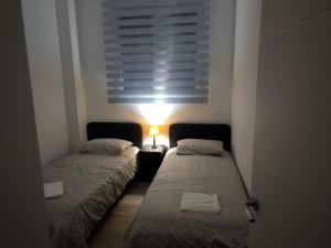 two beds in a small room with a window at Apartamento La Mandrágora in Arenas de Cabrales +13 photos