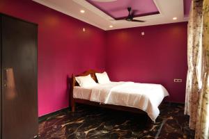 a bedroom with a bed with a purple wall at JPR Heritage Villa in Pondicherry +51 photos