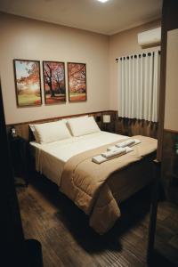 a bedroom with a large bed with three pictures on the wall at Candeias Hotel in Batatais +29 photos