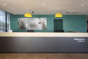 a lobby with a reception desk with yellow lights at City Express by Marriott Reynosa in Reynosa