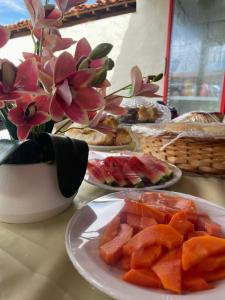 a table with plates of food and a vase with flowers at Morada do vento in São Miguel do Gostoso