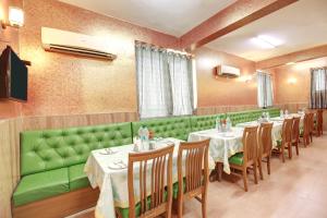 ein Restaurant mit einer grünen Couch und Tischen und Stühlen in der Unterkunft Marks in Noida