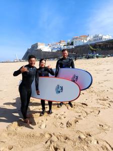 un gruppo di tre persone in piedi sulla spiaggia con le tavole da surf di 70's Hostel a Ericeira