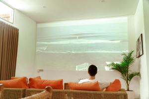 a man sitting on a couch looking out a window at the ocean at Casa Solisa in Kerobokan