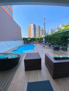 a patio with a hot tub and tables and chairs at pousada das manas in Torres
