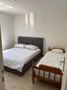 two beds in a bedroom with white walls at Elbas Apartman in Široki Brijeg