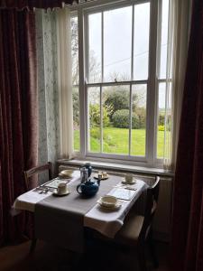 a table in front of a window with a table and chairs at Trevanger Farm Bed and Breakfast in Wadebridge