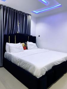 a large bed with white sheets and pillows at Spike apartments in Jibowu
