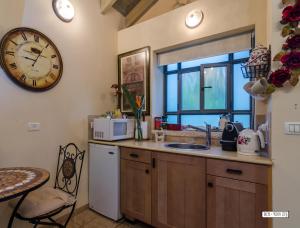 a kitchen with a sink and a clock on the wall at Zemer Lodging in Sede Eli‘ezer