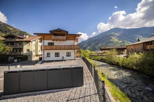 a building with a fence next to a river at RIVERSIDE RAURIS APARTMENTS in Rauris