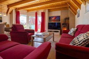 a living room with red couches and a tv at Ferienhaus Klapötke in Dorum-Neufeld