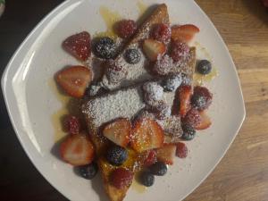 a white plate with strawberries and blueberries and powdered sugar at The Greannan Bed & Breakfast in Blackwaterfoot +35 photos