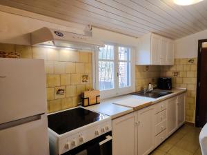 a kitchen with white cabinets and a sink and a refrigerator at Spiti Mata in Perítheia