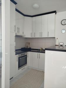 a kitchen with white cabinets and a black counter top at Smjestaj_S in Bijeljina