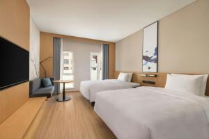 a hotel room with two beds and a flat screen tv at Fairfield by Marriott Hengdian in Dongyang