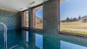 a bathroom with a swimming pool with a window at Luxury chalet - fireplace heated pool & sauna in Megève