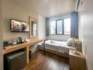 a room with a bed and a desk and a window at G Boutique Silom Hotel in Bangkok