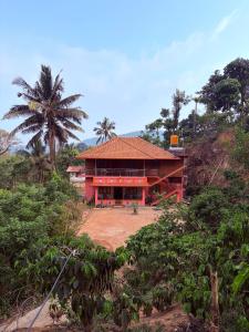 a red building with a palm tree in front of it at Dishaa Estate View Home Stay in Madikeri