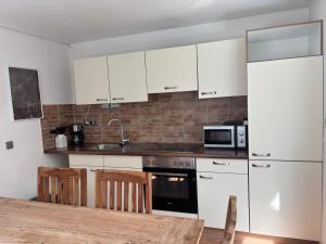 a kitchen with white cabinets and a wooden table at Wohnzeit-Köln in Cologne