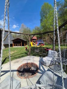 a swing with a fire pit and a playground at Cabana AFrame Olanesti in Băile Olăneşti