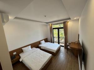a hotel room with two beds and a window at Khách sạn Lâm Hà - Laha Hotel in Riong Serignac