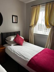 a bed with a pink blanket and a window at Dunroamin Self-Catering Apartment in Aviemore