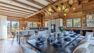 a dining room with a table and chairs and a kitchen at Luxury chalet - fireplace heated pool & sauna in Megève