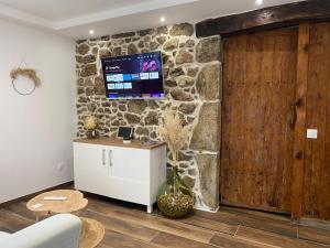 a living room with a stone wall and a tv at Le Clos de Narco in Vernosc-lès-Annonay