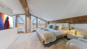 a bedroom with a large bed and a tv at Luxury chalet - fireplace heated pool & sauna in Megève +88 photos
