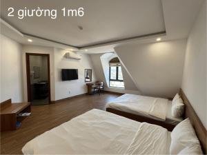 a hotel room with two beds and a tv at Khách sạn Lâm Hà - Laha Hotel in Riong Serignac +10 photos