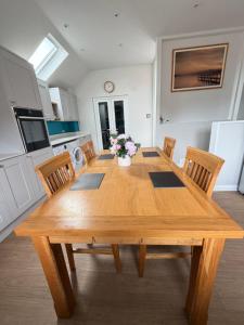 a wooden dining room table with chairs and flowers at Teran the apartment in Timsbury +12 photos