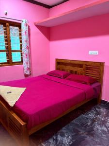 a bedroom with pink walls and a large bed at Dishaa Estate View Home Stay in Madikeri