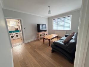 a living room with a black leather couch and a table at Teran the apartment in Timsbury