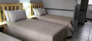 a hotel room with two beds with white sheets at AMBROZIA Apartment-self catering-2bed2bath in Bloemfontein