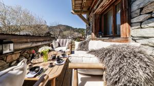 a balcony with couches and a table on a building at Luxury chalet - fireplace heated pool & sauna in Megève