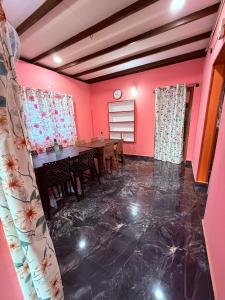 a dining room with a table and pink walls at Dishaa Estate View Home Stay in Madikeri