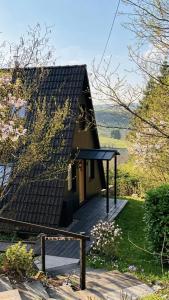 a small house with a wooden deck and a bench at Designer chalet with gorgeous Eifel panorama in Kerschenbach