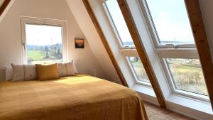 a bedroom with three windows and a bed with yellow sheets at Designer chalet with gorgeous Eifel panorama in Kerschenbach