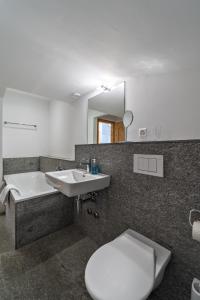 a bathroom with a toilet and a sink and a tub at Chesa Nair - Surlej in Surlej +11 photos