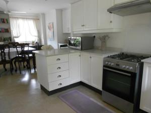 a kitchen with white cabinets and a stove at Chickpea Villa in Bergview