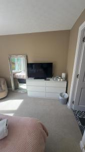 a bedroom with a large television and a mirror at Fairwinds in Inverness