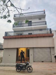 a man standing next to a motorcycle in front of a building at Sai holidays in Ayodhya