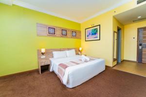 a bedroom with a large bed and yellow walls at HIG Hotel & Convention in Kuah