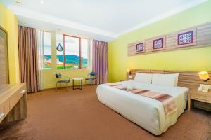 a bedroom with a large white bed and yellow walls at HIG Hotel & Convention in Kuah
