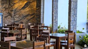 a restaurant with tables and chairs and a stone wall at Golden Sky Hotel & Wellness in Kandy