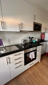a kitchen with white cabinets and a black counter top at Apartamento La Hera in Belvis de Monroy +13 photos