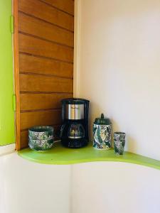 a coffee maker on a shelf with three jars at Chambre indépendante in Basse-Terre